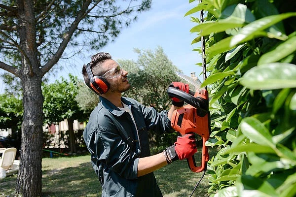 Mann schneidet eine Hecke, Werkzeugstandort ist durch Beacons bekannt