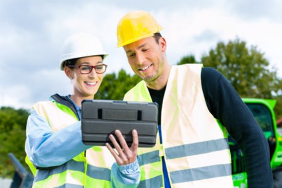 Werknemers op de bouwlocatie kijken naar een tablet