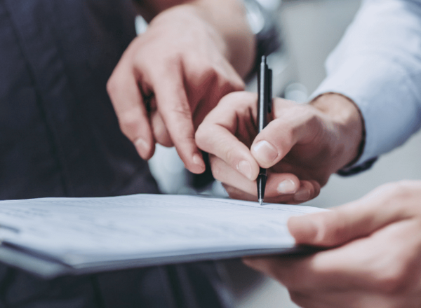 Zwei Personen füllen gemeinsam ein Formular auf einem Klemmbrett aus