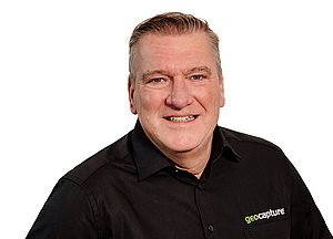 Mitarbeiter von geoCapture in schwarzem Hemd lächelt in die Kamera