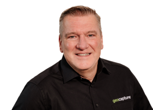 Porträt eines geoCapture Mitarbeiters im schwarzen Firmenhemd vor weißem Hintergrund, professionelles Businessfoto