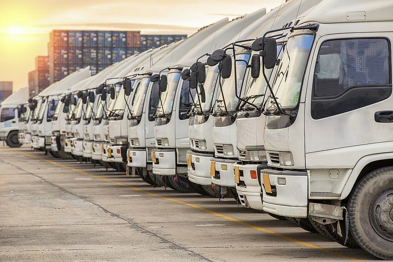 Eine Flotte von LKW auf einem Parkplatz, GPS-Ortung für digitales Fuhrparkmanagement.