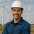 Lächelnder Ingenieur mit Schutzhelm vor Windkraftanlagen – Fachkraft für erneuerbare Energien und Windenergie-Projekte