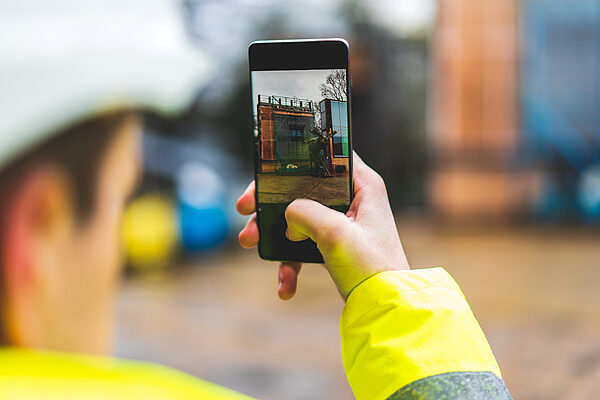 Mitarbeiter auf einer Baustelle mit Smartphone macht ein Foto