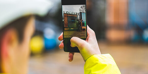 Mitarbeiter auf einer Baustelle mit Smartphone macht ein Foto