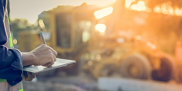 Auf einem Tablet unterschreibt ein Mann ein digitales Bautagebuch