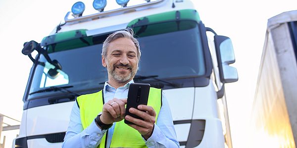 Lkw-Fahrer mit Smartphone vor seinem Fahrzeug zur digitalen Touren- und Auftragsverwaltung mit geoCapture.