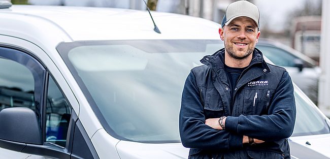 Servicetechniker vor Firmenfahrzeug der Jakob Wassertechnik, Mitarbeiterporträt im Außeneinsatz