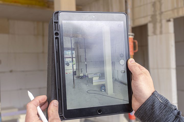 Mitarbeiter dokumentiert den Arbeitsbereich auf einer Baustelle mit einem Tablet.